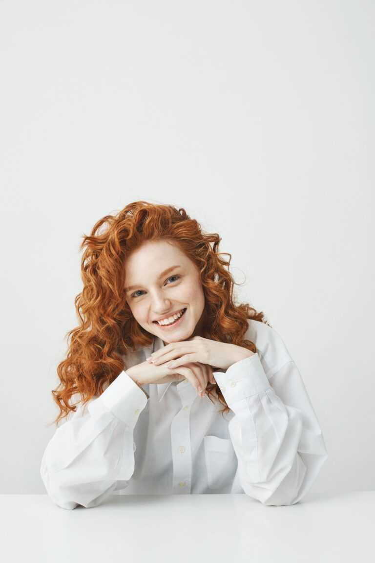 beautiful_redhead_woman_with_curly_hair_smiling_looking_camera_sitting